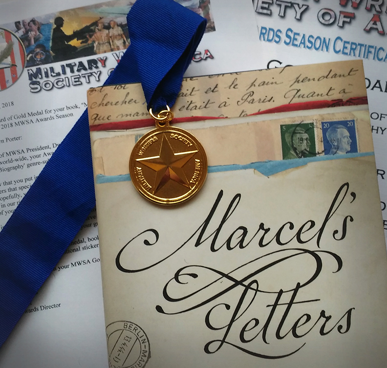 Gold Medal from Military Writers Society of America laying on top of book "Marcel's Letters"