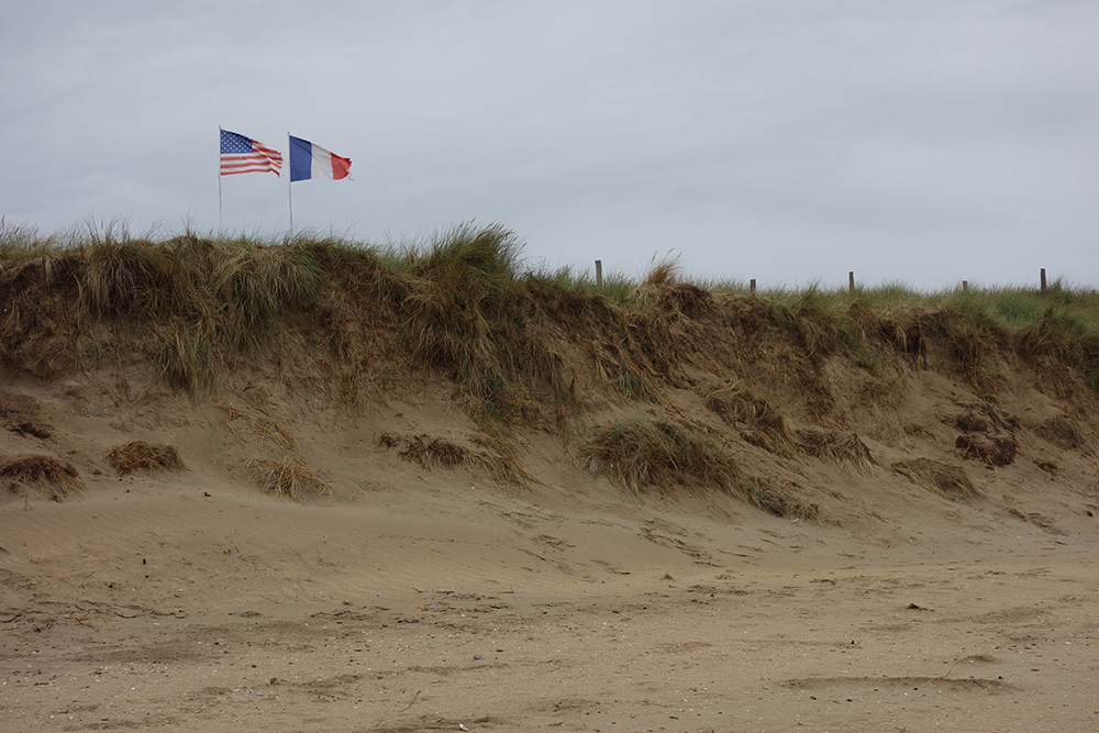 Utah beach, Normandy, with American and French flags flying in distance